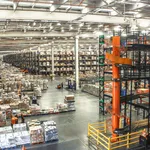 Almacén logístico con estanterías altas y carretilla elevadora naranja