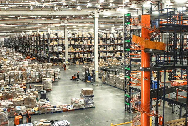 Almacén logístico con estanterías altas y carretilla elevadora naranja
