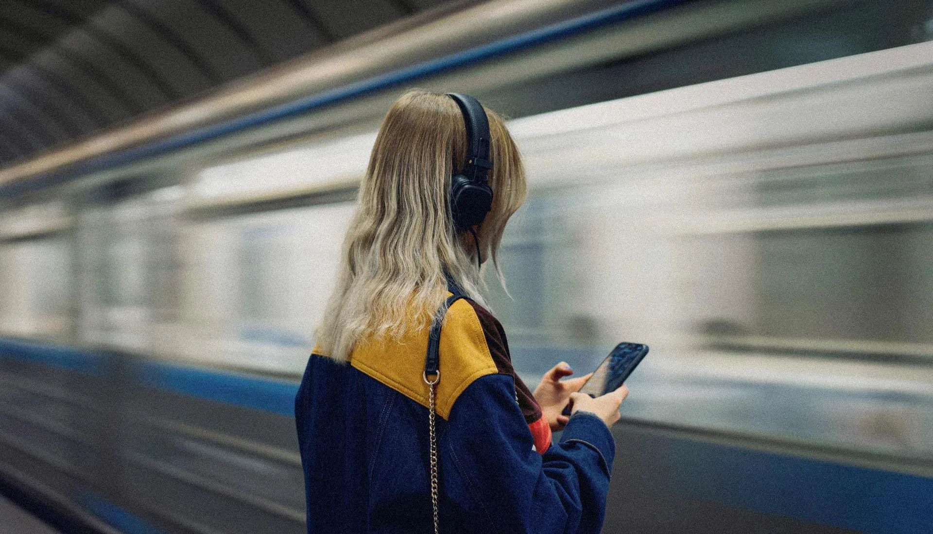 Viajera esperando en un andén con un tren en marcha